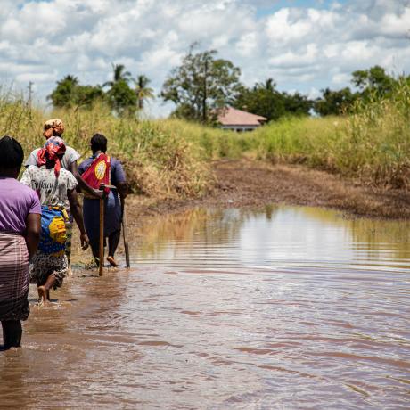 women wade through flood water in mozambique
